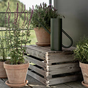Stelton Bloom Watering Can in matte dark green powder-coated stainless steel with long slender spout and seamless handle design.