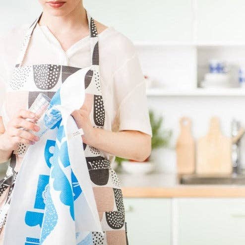 Person wearing a pink, black, and white graphic-pattern linen-cotton apron by Hanna Konola in a kitchen setting.