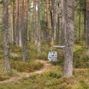 Person holding a black forest-pattern linen-cotton tote bag by Laura Carlin, 15" x 17" in a forest setting