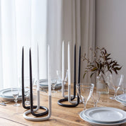 Architectmade Gemini Candleholder by Peter Karpf in matte black and matte white stainless steel, styled with matching taper candles in a sculptural curved form.