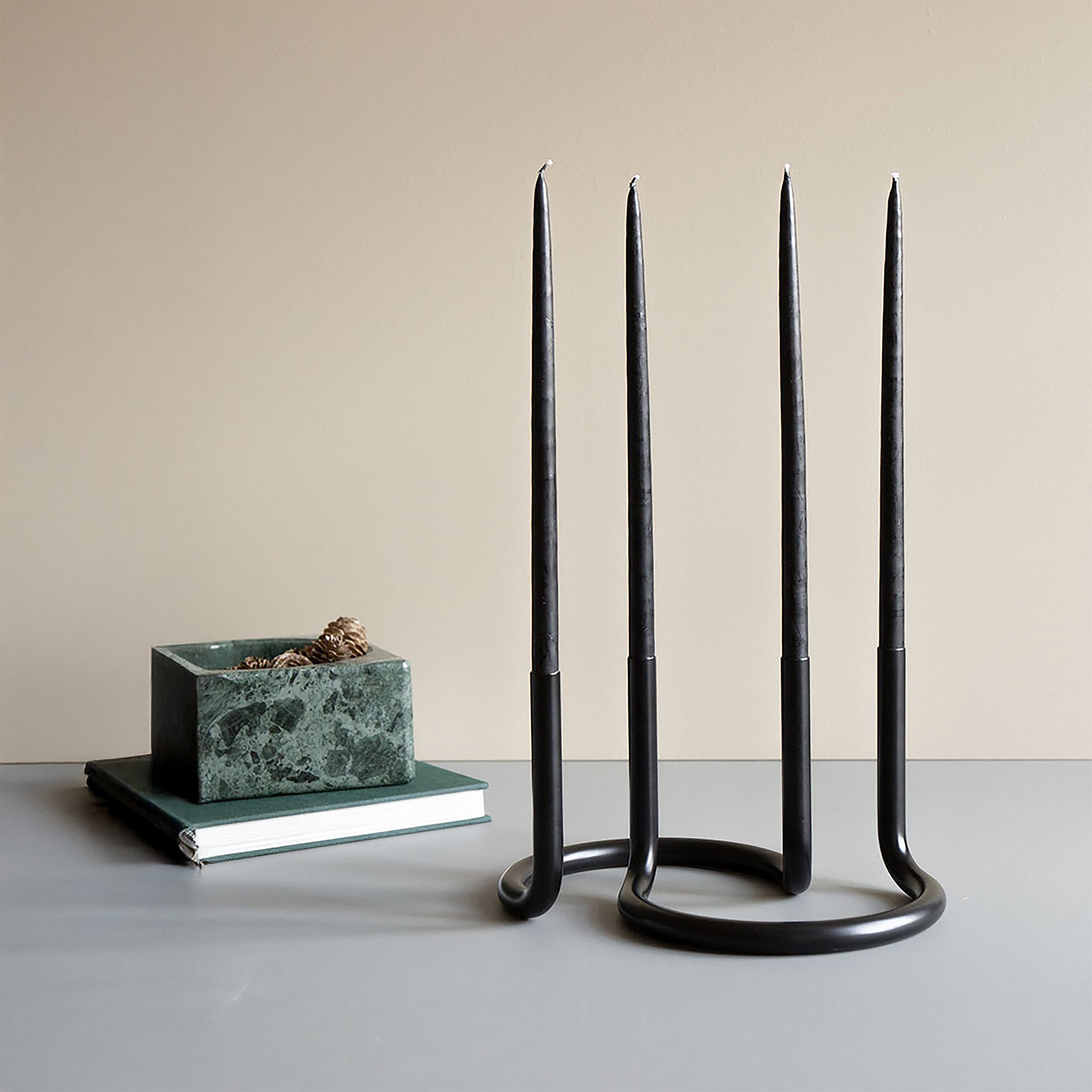 Architectmade Gemini Candleholder by Peter Karpf in matte black stainless steel, styled with matching black taper candles in a sculptural curved form.