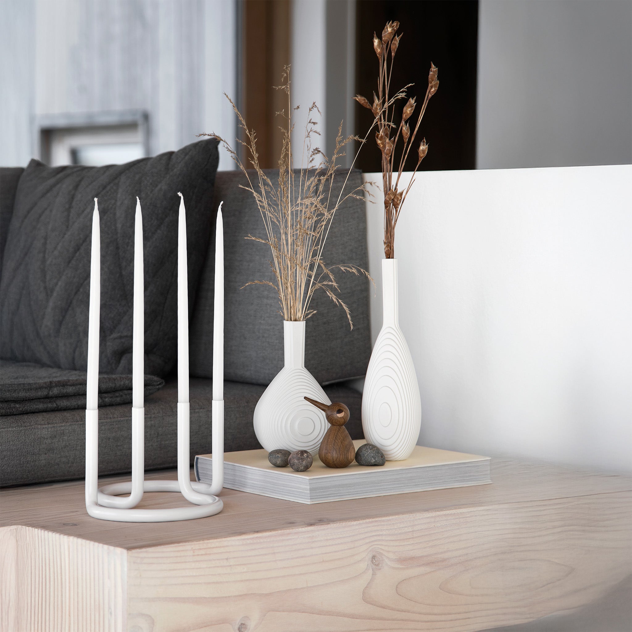 Architectmade Gemini Candleholder by Peter Karpf in matte white stainless steel, styled with matching white taper candles in a sculptural curved form.
