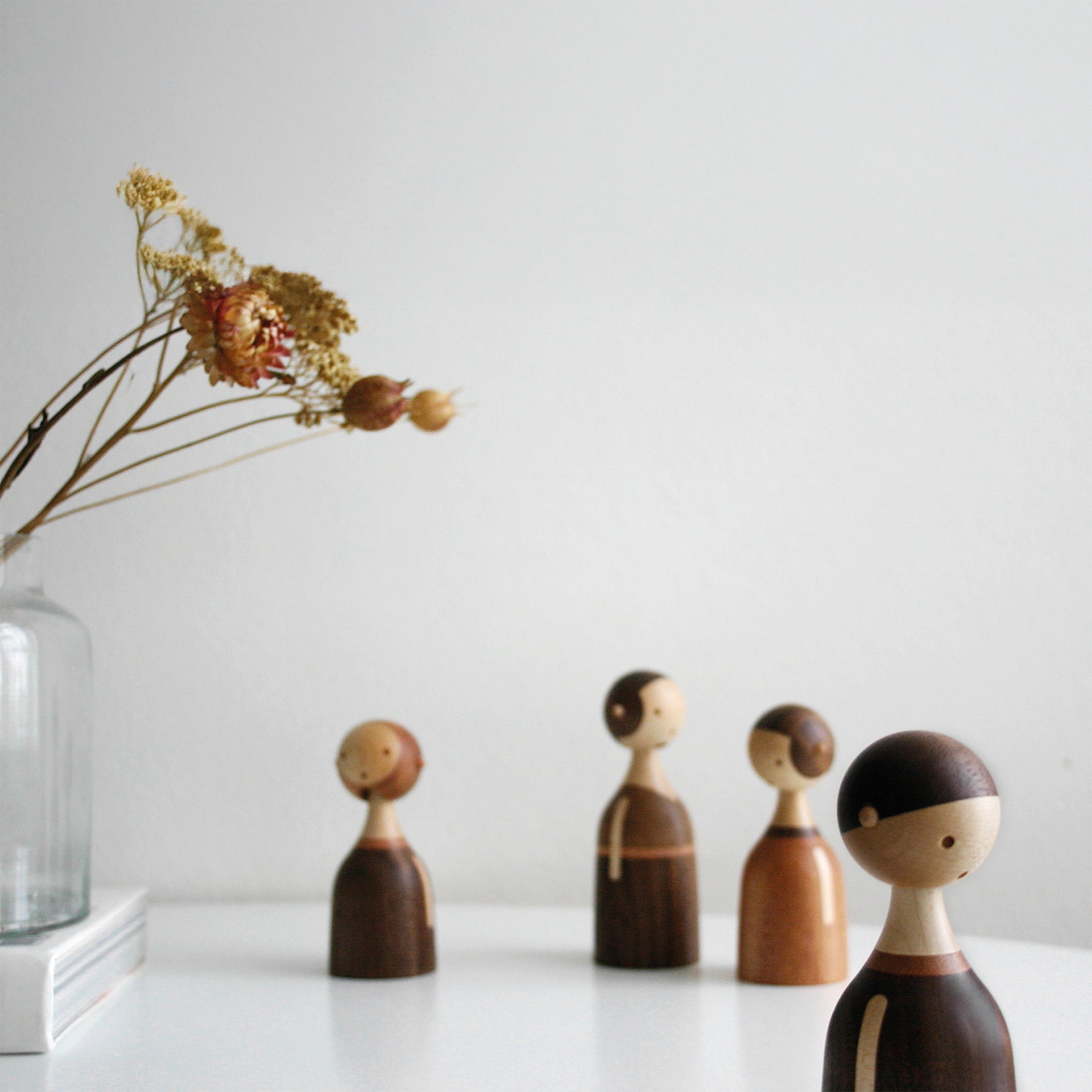 Architectmade Kin figurines by Lars Beller Fjetland, handmade in walnut, mahogany, and maple with tilting heads, shown in a mix-and-match constellation.