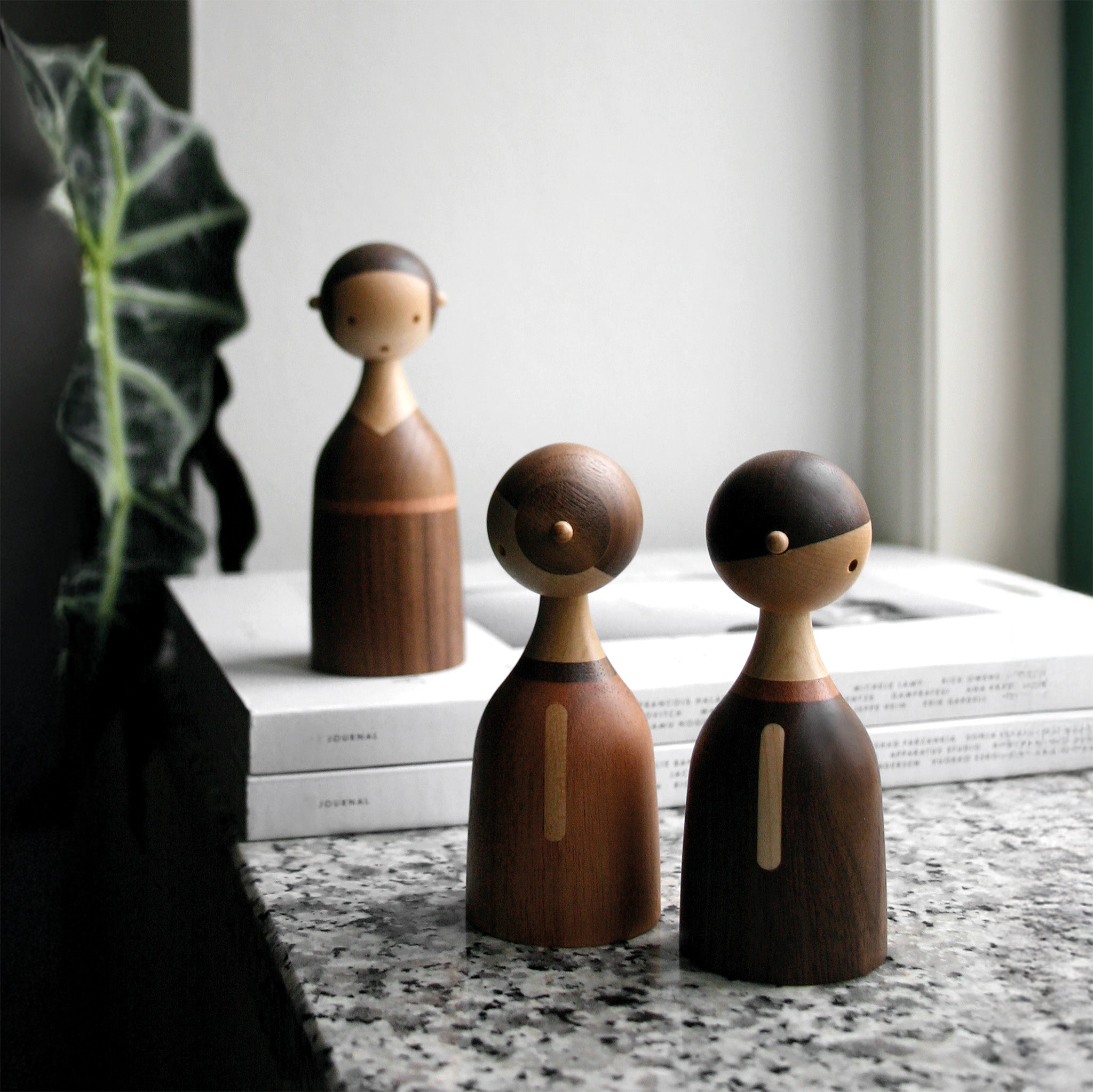 Architectmade Kin figurines by Lars Beller Fjetland, handmade in walnut, mahogany, and maple with tilting heads, shown in a mix-and-match constellation.
