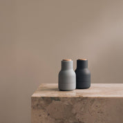 Audo Copenhagen Small Bottle Grinder in bottle-shaped form with beech lid. Compact Nordic salt and pepper mill with inverted, mess-free design.