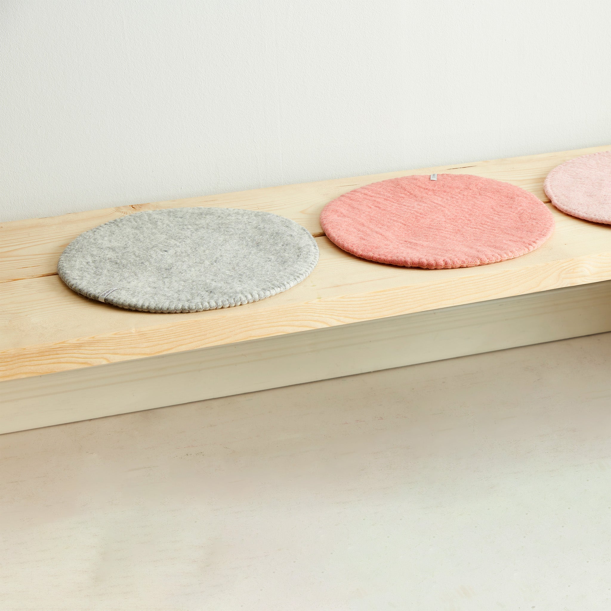 Aveva Seat Cushion in wool felt, available in raw grey or graphic patterns. Round portable chair pads in two sizes, designed in Sweden.