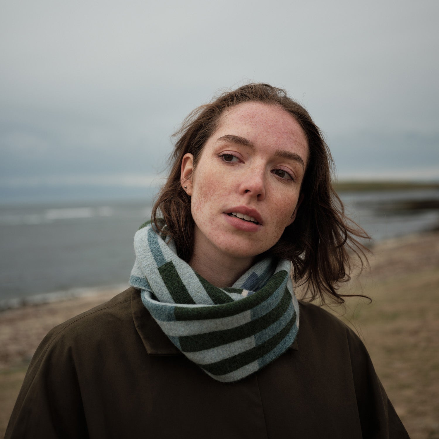Hilary Grant Harbour Circle Scarf with rhythmic coastal stripes in soft blues, greens, and greys, reversible fine-gauge lambswool knit, handmade in Orkney, Scotland.