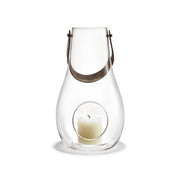 Holmegaard Design With Light H45 mouth-blown glass lantern with full-grain leather strap by Maria Berntsen, available in clear. 17.7 inches tall.