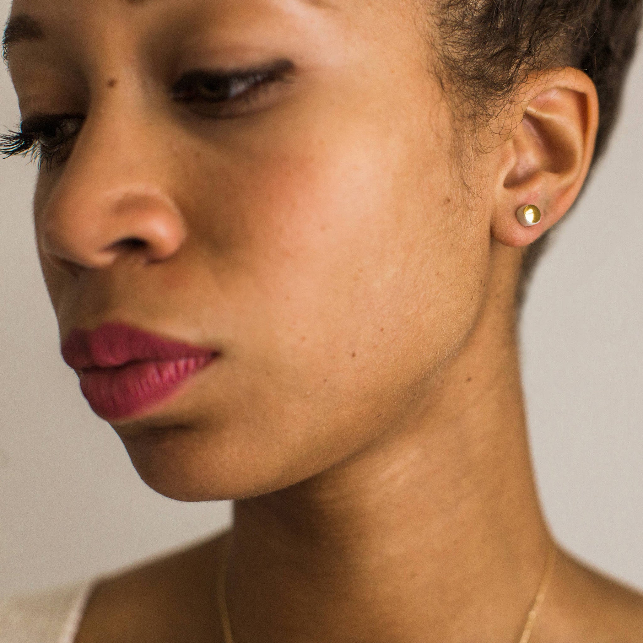 Gold porcelain dot stud earrings handmade by Jenna Vanden Brink, ¼″ shiny luster finish with titanium posts