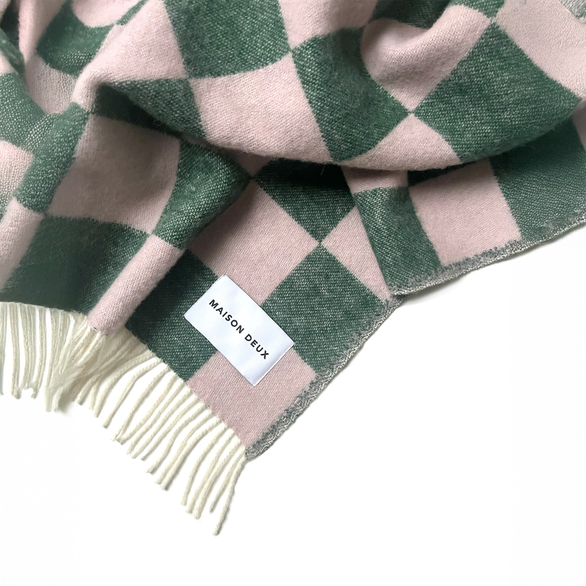 Maison Deux Checkerboard Blanket in green and pink lambswool with bold reversible checkerboard design.
