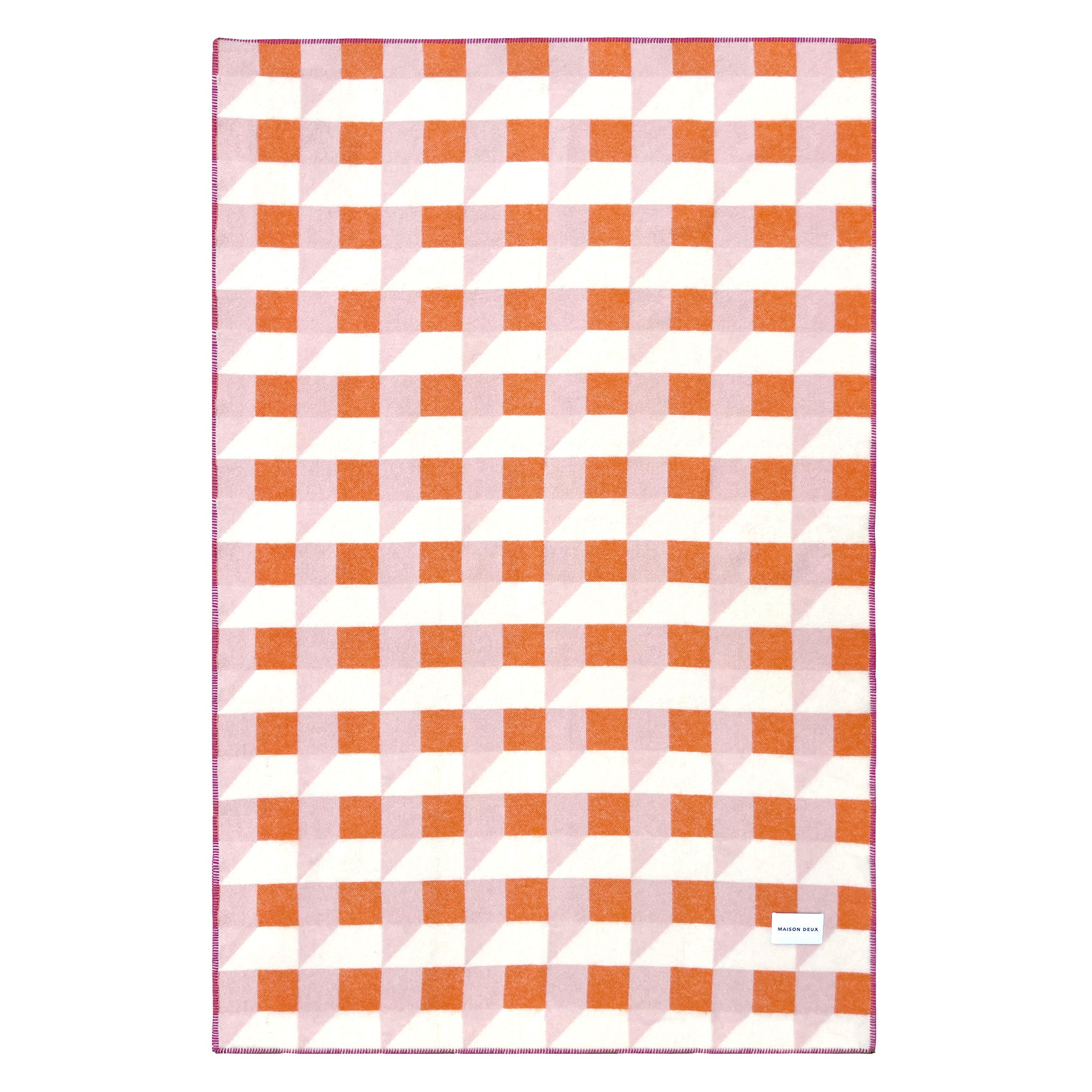 Maison Deux Cubics Blanket in pink and carrot, reversible wool throw with cubic pattern and fringed edges, oversized for cozy lounging.