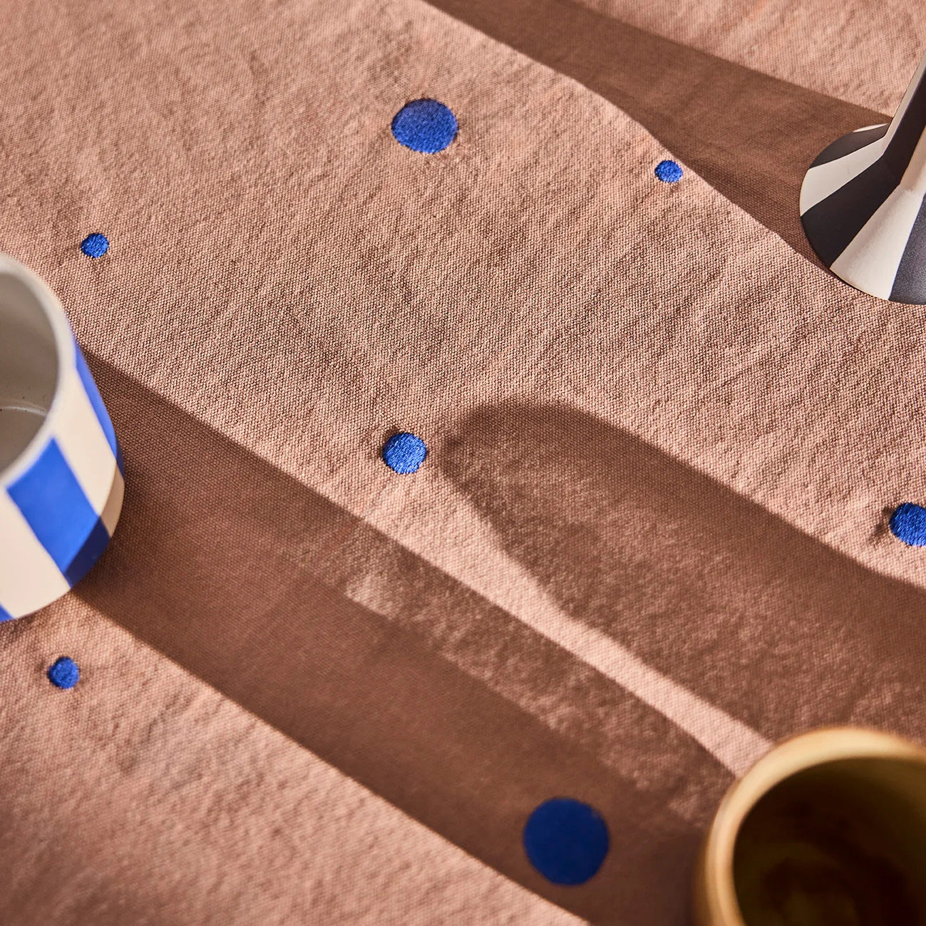 OYOY Nori Tablecloth in terracotta with scattered optic-blue dots, 100% organic cotton, available in two sizes.