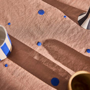 OYOY Nori Tablecloth in terracotta with scattered optic-blue dots, 100% organic cotton, available in two sizes.