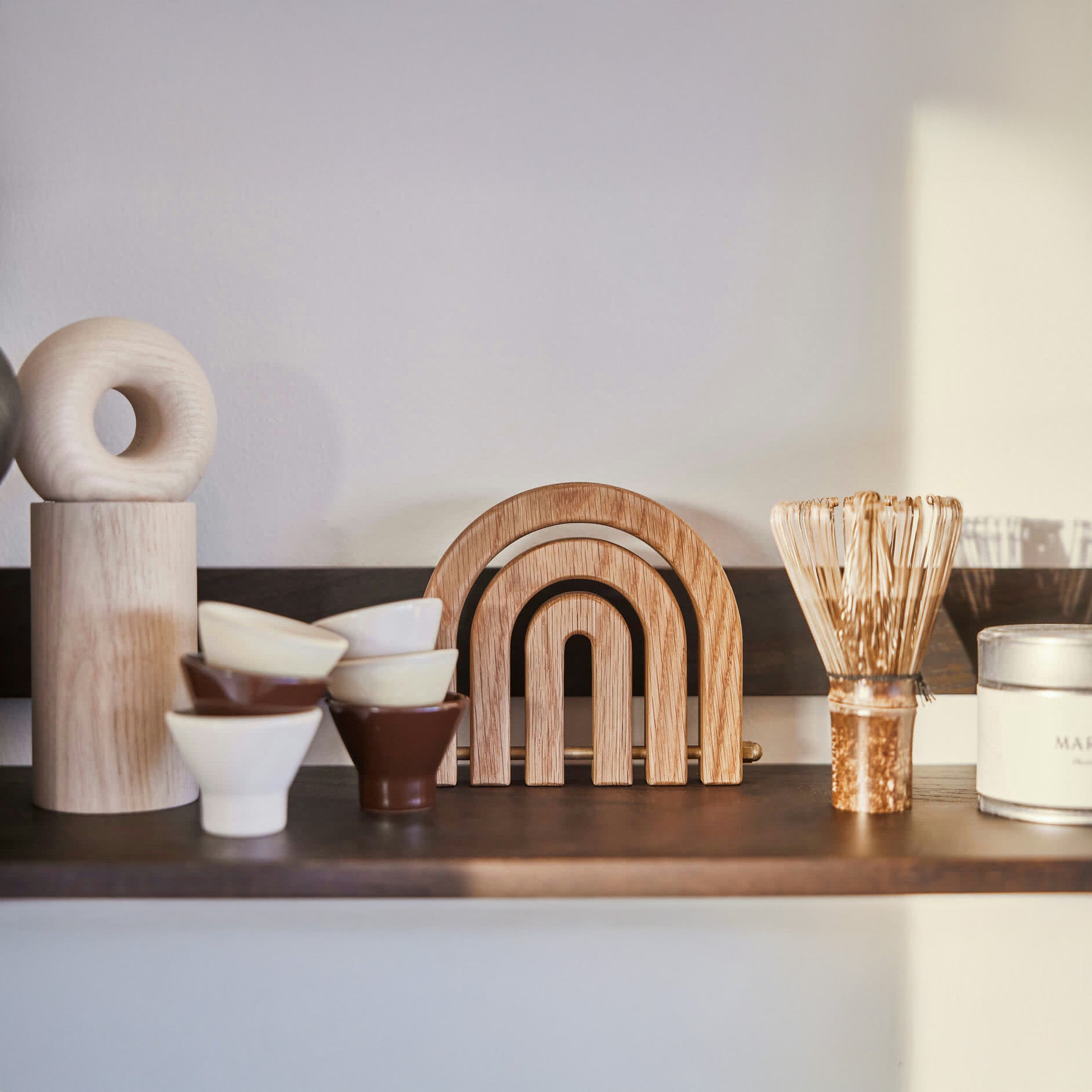 OYOY Living Design Rainbow Wooden Trivet in oak with brass details. Foldable rainbow shape expands for hot pots or hangs as wall décor.