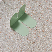 Tortuga Forma Large Bookend in cactus green solid steel, oversized arc design for supporting art books, cookbooks, or vinyl.