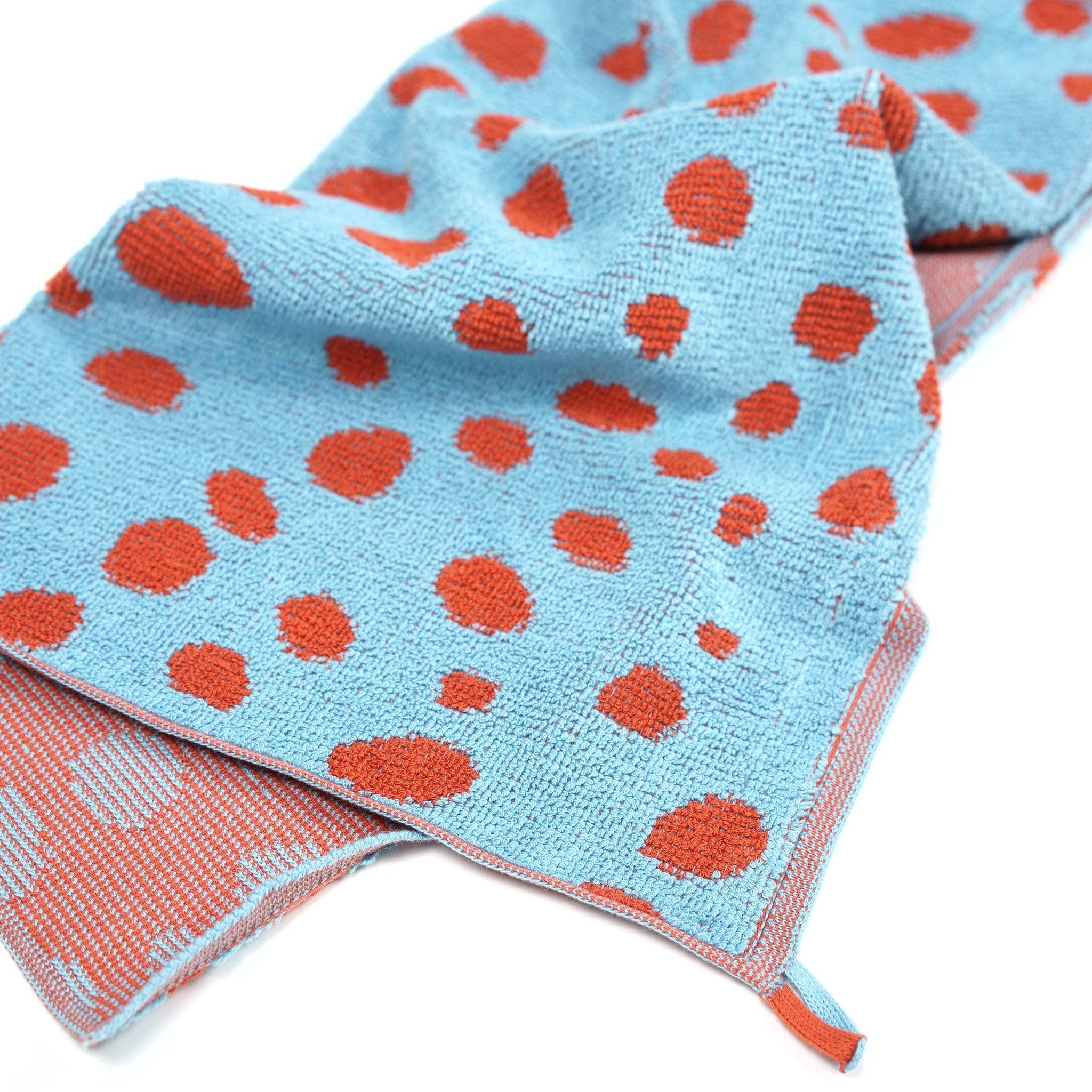 Towel Studio Pebbles Guest Towel in Sky Blue and Brick Red, 50 × 50 cm with terry front and knit back.
